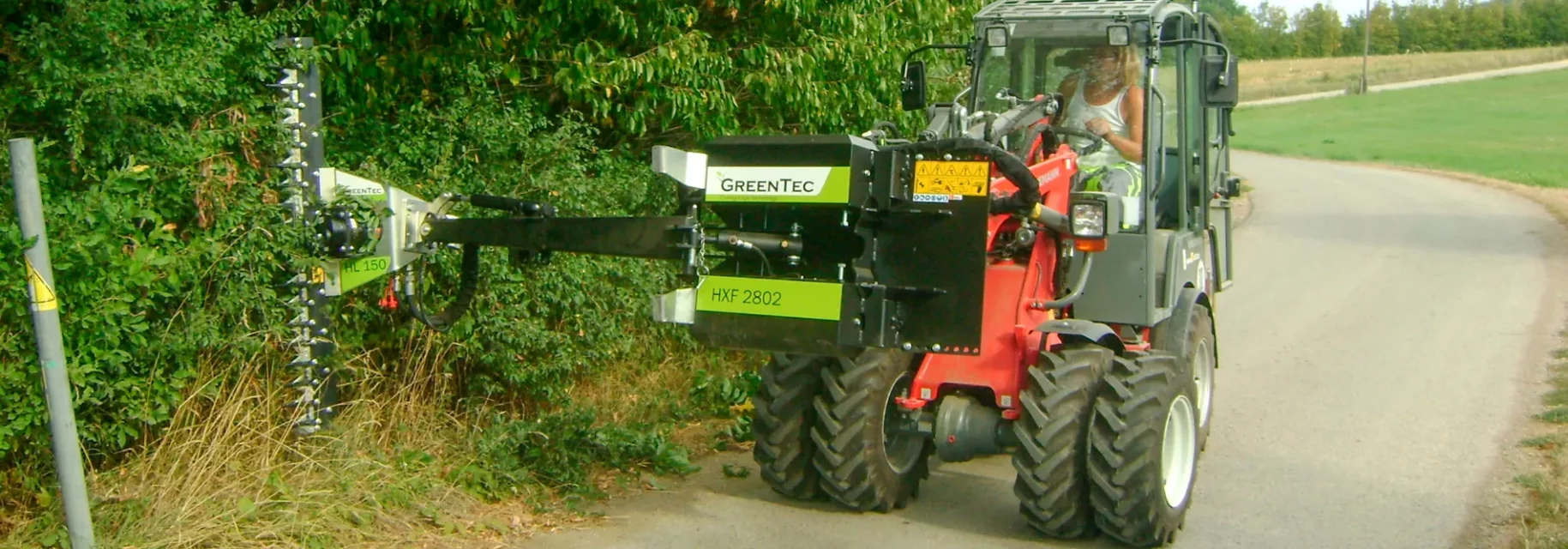 Hydraulic hedge trimmer mounted on skid steer loader